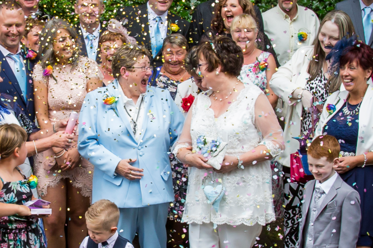 bride and bride smiling at each other with confetti.